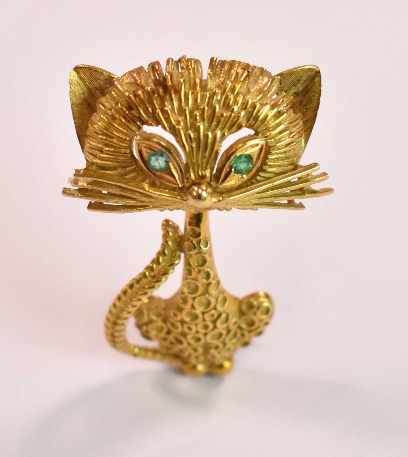 An 18ct yellow gold brooch in the form of a stylised cat with emeralds set for the eyes, length