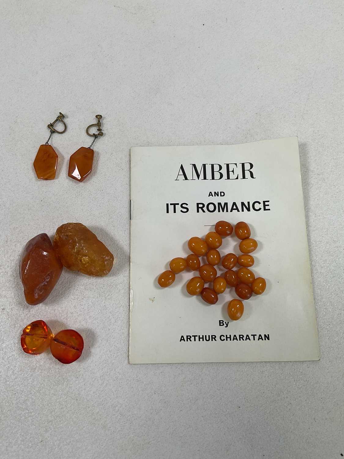 A group of loose amber beads, two large rough cut sections of amber, a split amber bead and a pair