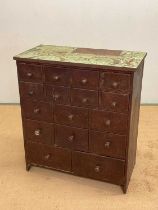 A stained pine workshop cabinet with an arrangement of sixteen drawers, heavily waxed with green