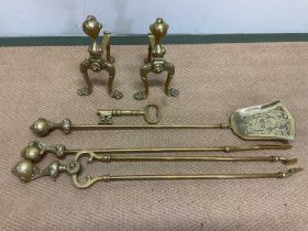 A brass fire companion set comprising two fire dogs, coal shovel, poker, tongs, and a large brass