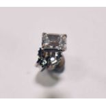 A white metal single diamond ear stud, the emerald cut stone weighing approx 0.33ct, corner claw set