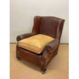 An early 20th century leather armchair with studded arms and side panels, height at back 84cm, width