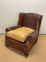 An early 20th century leather armchair with studded arms and side panels, height at back 84cm, width