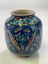 A Palestinian vase with floral and leaf decoration in shades of blue, turquoise, ochre and green,