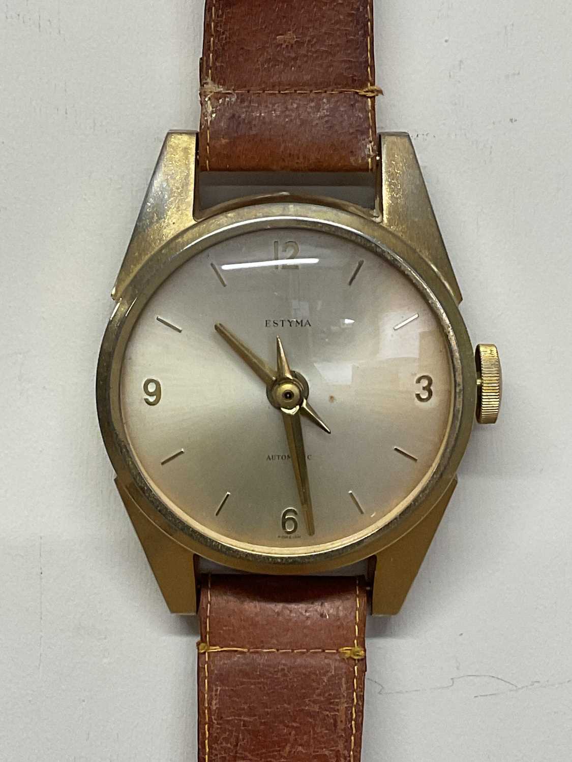 ESTYMA; a wall clock styled as a wristwatch on leather strap, height 78cm, width 12cm