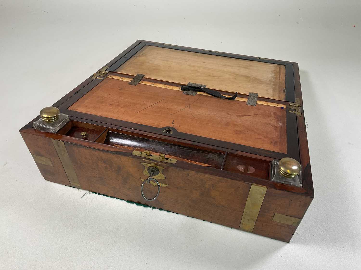 A burr walnut writing slope with brass strapping and corners, brass topped inkwells, escutcheons and