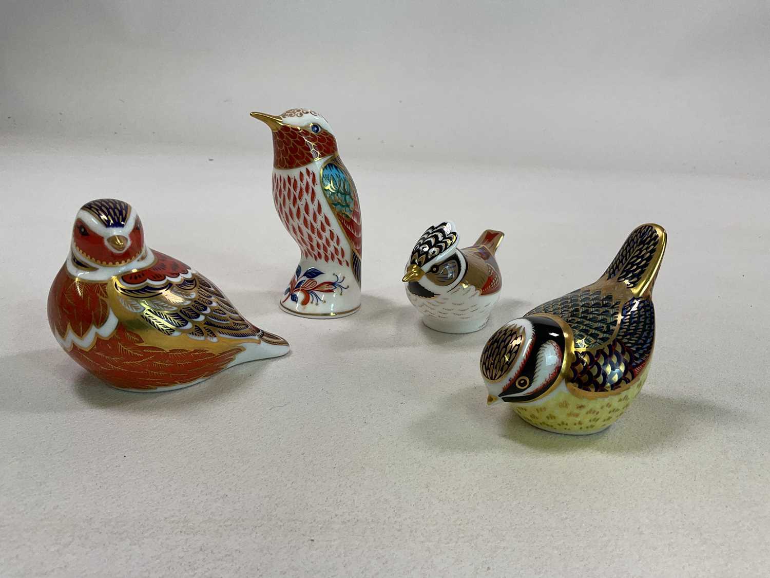 ROYAL CROWN DERBY; a collection of four bird paperweights including a Collectors' Guild Crested