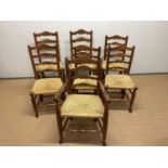 Six ladder back rush seated dining chairs and a carver, back height on two 97 cm, other five 94cm (