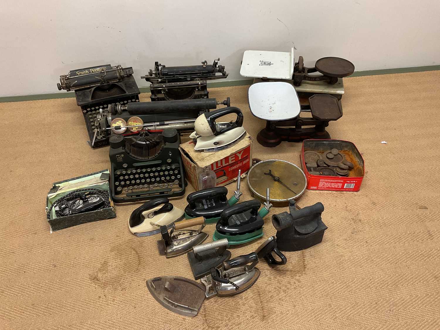 A collection of typewriters, scales including Avery shop scales and weights, vintage irons and other
