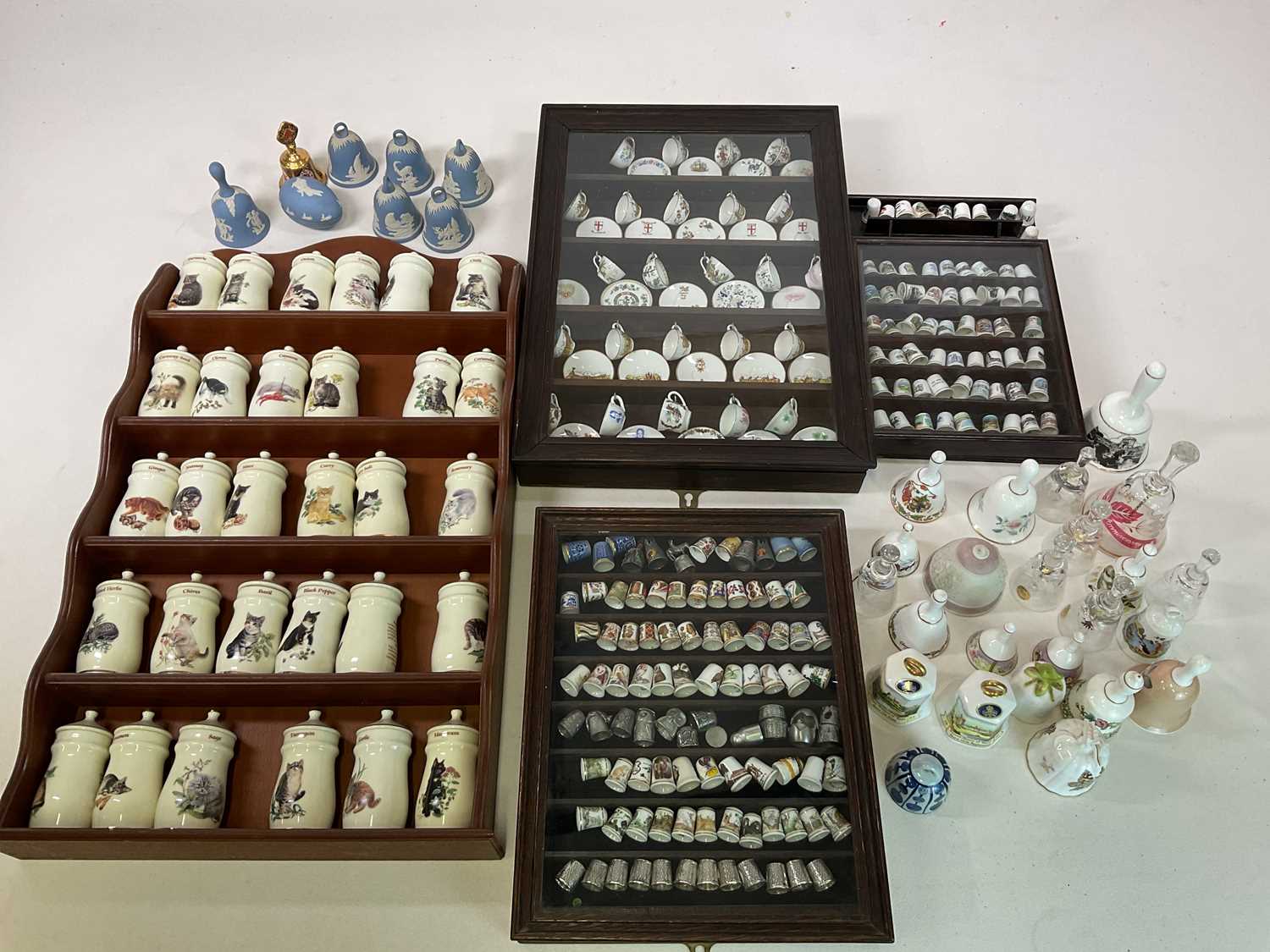 A collection of mainly miniature ceramics including cups and saucers, thimbles, bells and cat