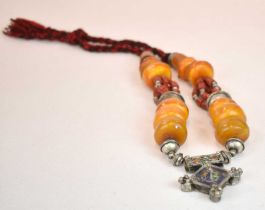 A Sudanese amber white metal and cloth necklace set with several large pieces of eggyolk/