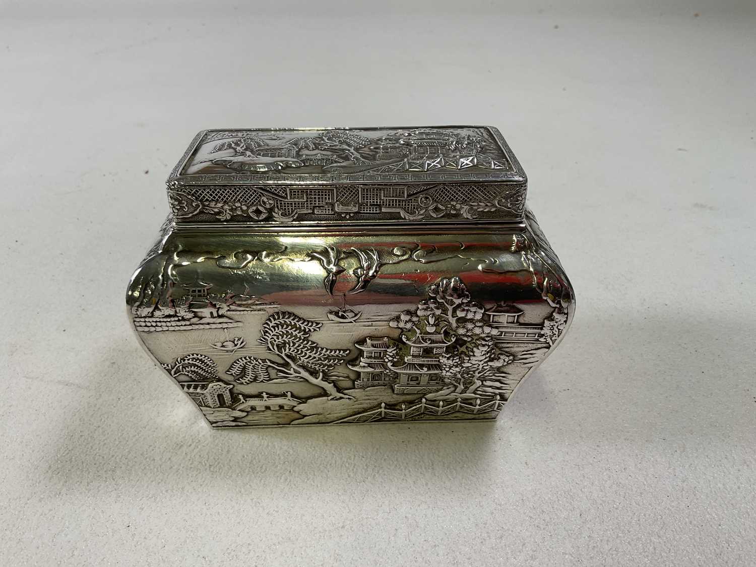 A circa 1900 Chinese white metal tea caddy with lift-off cover, inner liner and bombe body decorated