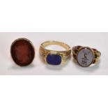Three yellow metal rings, one set with a carved carnelian, size O, 4.9g approx one with central