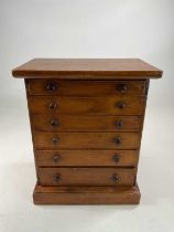 A six drawer specimen cabinet containing samples of ore and fossils, with original sales label on