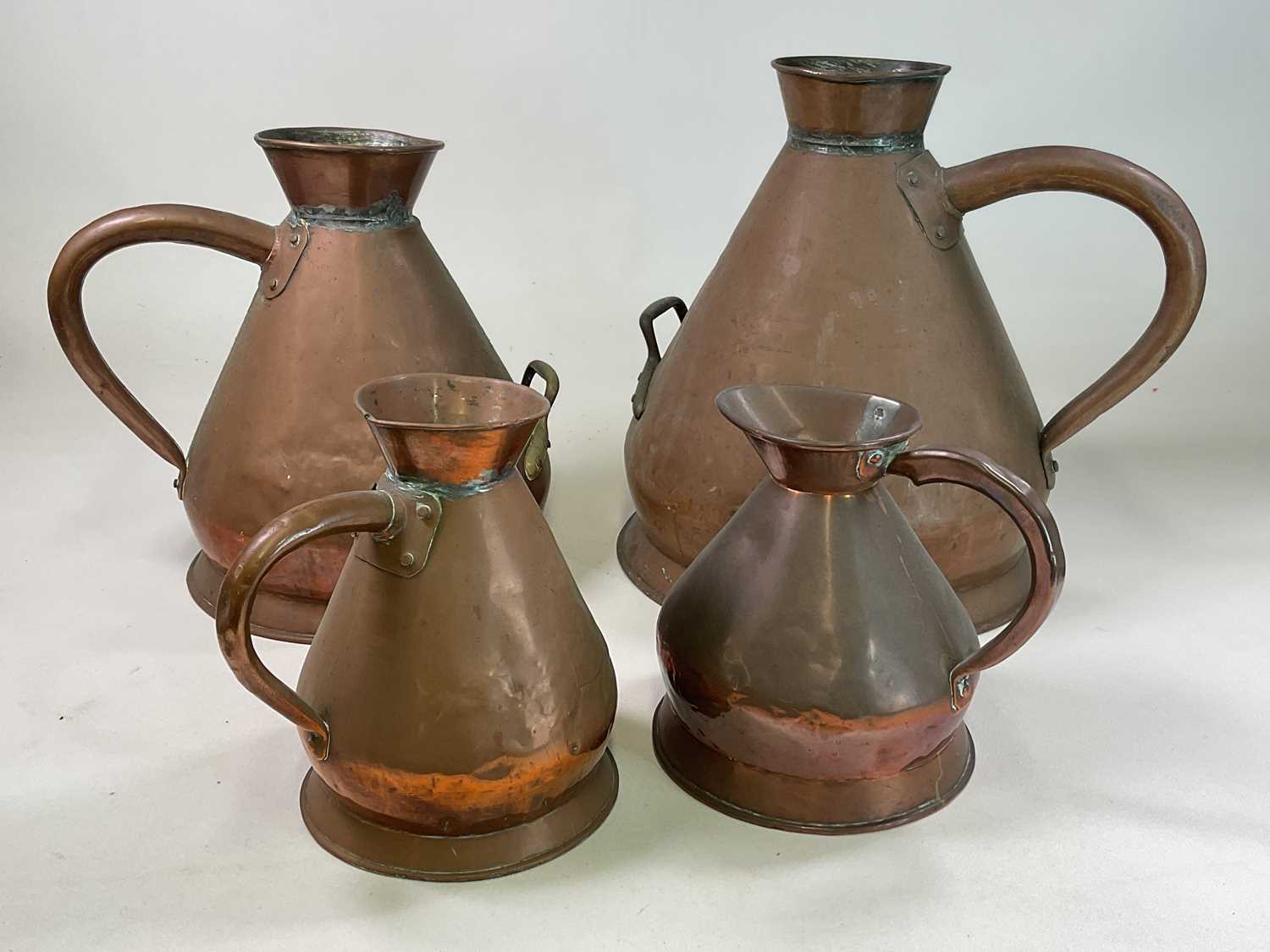A set of three graduated copper harvest jugs comprising five gallon, three gallon and a one