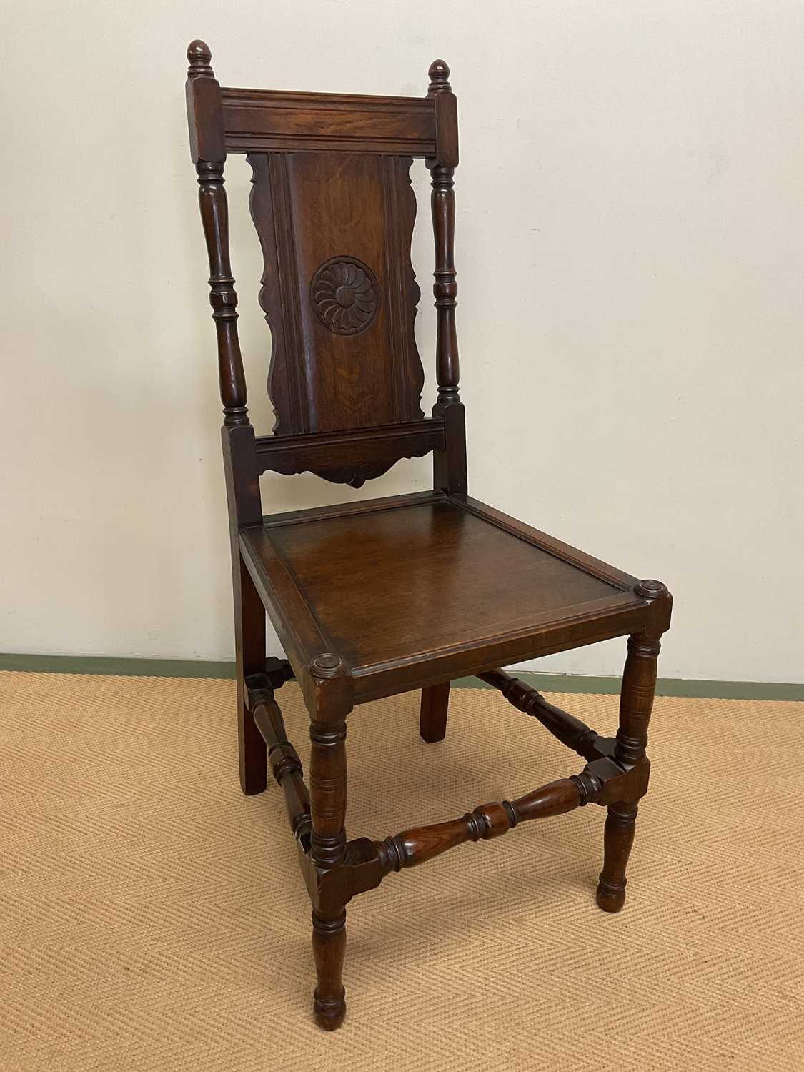 A 19th century oak panel back side chair with panel seat and carved central motif of a flower on the