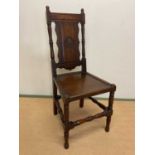 A 19th century oak panel back side chair with panel seat and carved central motif of a flower on the