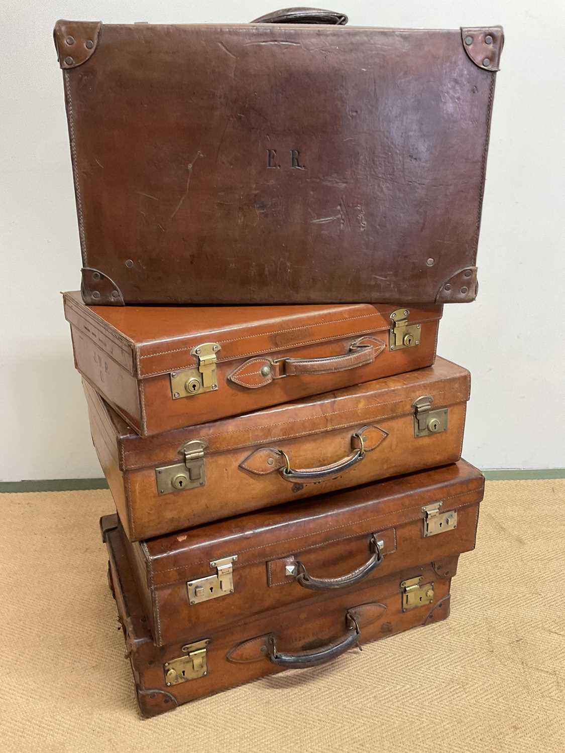 Five 20th century leather suitcases, largest 66 x 41 x 20cm.