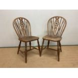 A pair of elm wheelback dining chairs, height of back 85cm.