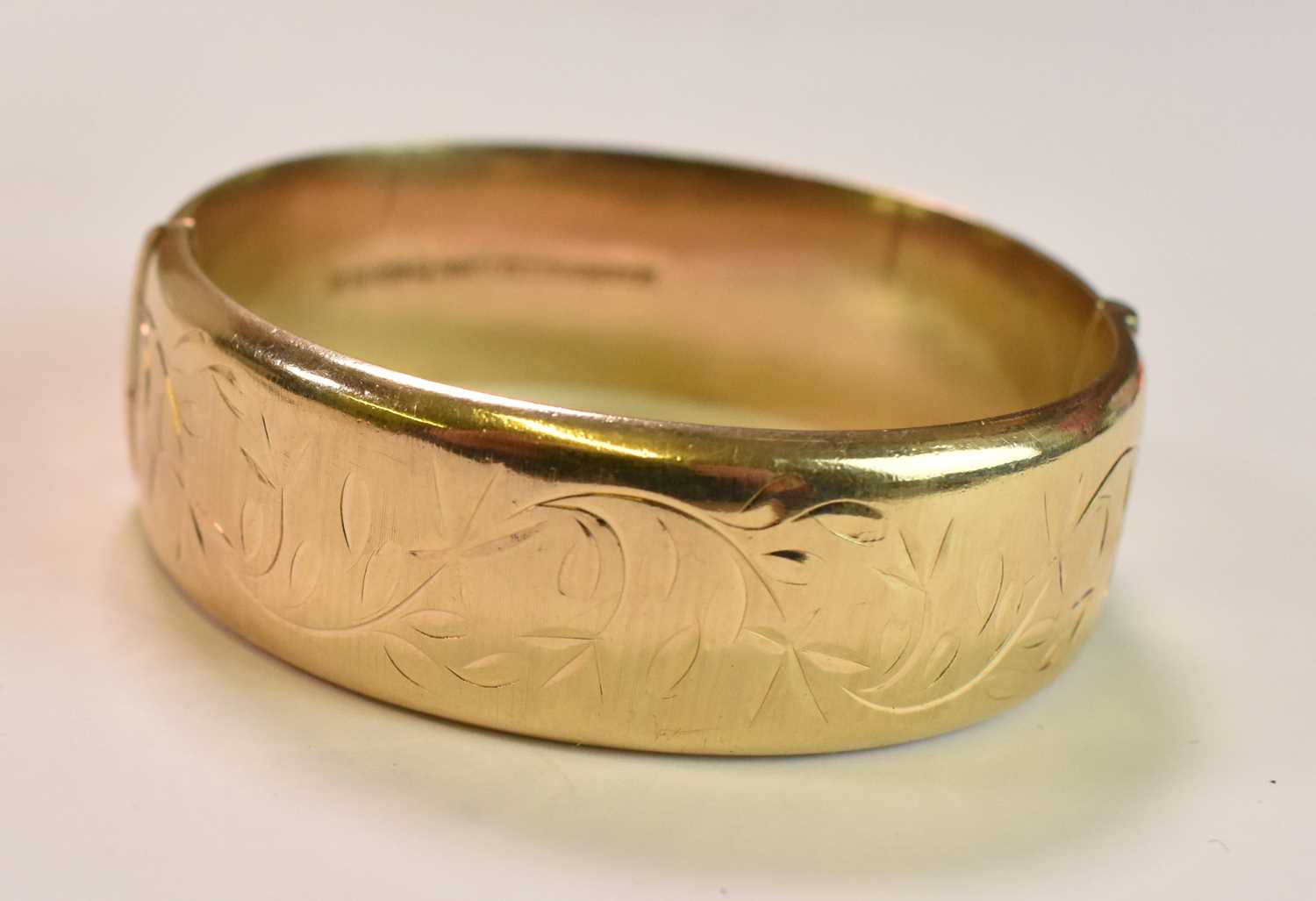 A 9ct yellow gold oval engraved hinged bangle, internal width 57mm, approx 23.2g. - Image 2 of 3