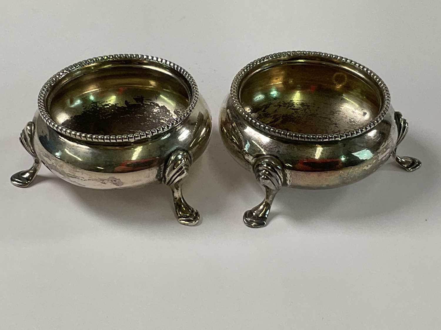 ROBERT HENNELL; a pair of Victorian hallmarked silver open salts raised on three scrolling supports,