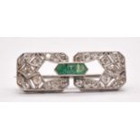 An Art Deco white metal emerald and diamond brooch set with three emeralds to the central raised