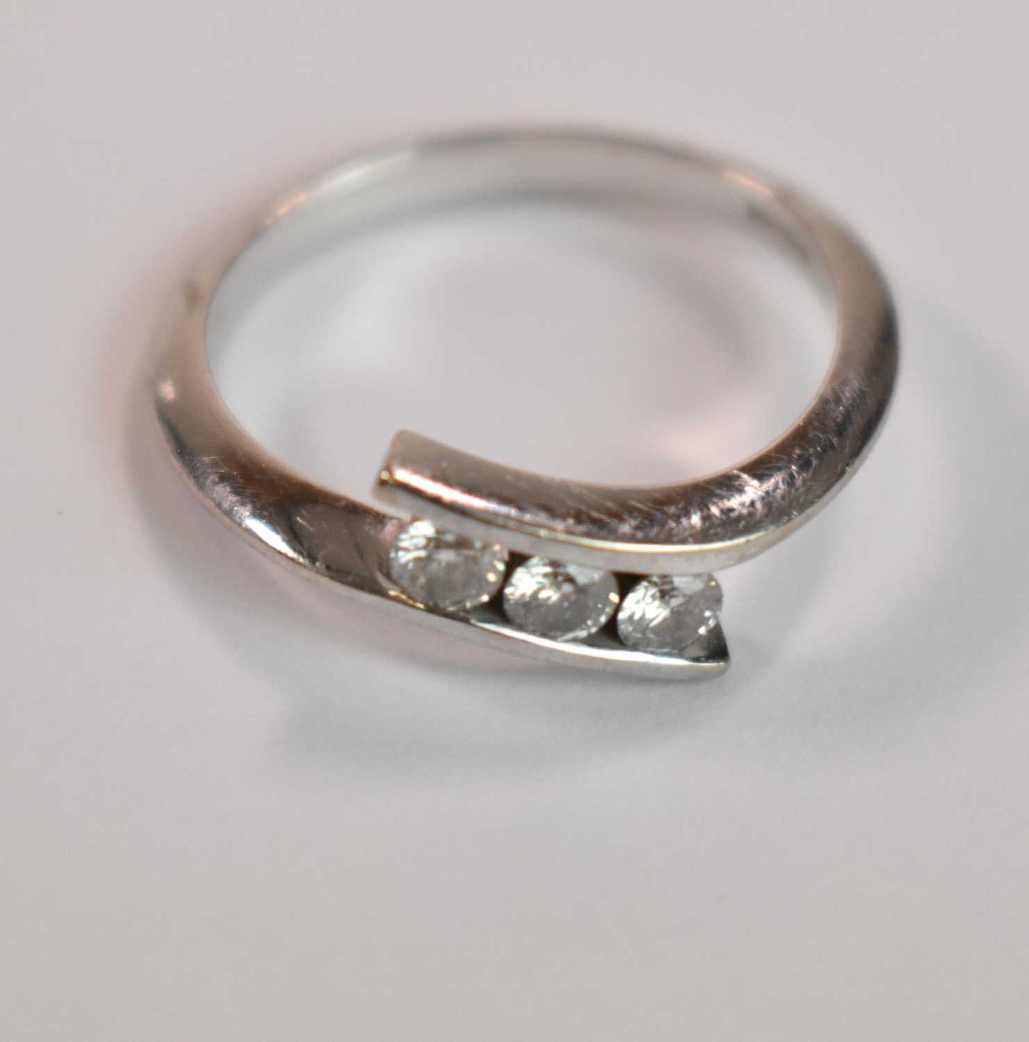 An 18ct white gold and diamond three stone channel set ring, size P, accompanied with the