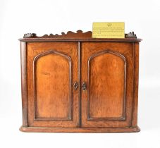 An unusual oak coin collectors' cabinet with shaped three-quarter gallery top above pair of panelled