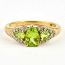 A 9ct gold dress ring with claw set pear-shaped peridot flanked by two claw set peridots within