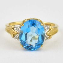 A 9ct gold dress ring with large claw set blue stone and two tiny diamond chips to each shoulder,