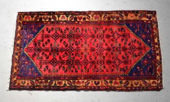A hand knotted red ground rug with geometric decoration, 192 x 105cm.