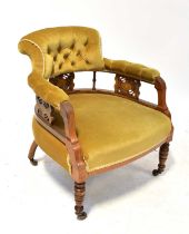 An Edwardian mahogany open elbow tub armchair, button upholstered in a mustard velour with pierced