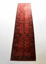 A red ground runner with geometric pattern, 263 x 67cm.