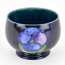WALTER MOORCROFT; a small tube-lined bowl with 'Pansy' decoration on blue ground, impressed