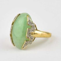 A 9ct gold ring set with oval pale green jade mounted either side with contemporary white stone