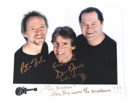 THE MONKEES; a colour promotional photograph showing three members of the band, bearing signatures