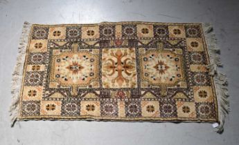 A beige ground rug with floral medallions within a geometric border, 144 x 79cm.