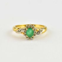 An 18ct gold ring with marquise cut claw set emerald within a border of small white stones, white