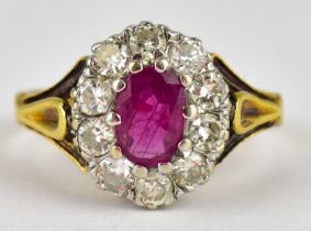 A 9ct gold ring with claw set oval cut ruby within a border of claw set tiny brilliant diamonds,