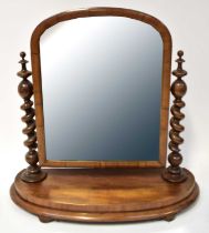 A Victorian mahogany swivel mirror with twist turned side columns on stepped oval base, raised on