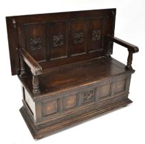 An early 20th century oak monk's bench, the lower section with storage compartment, raised on