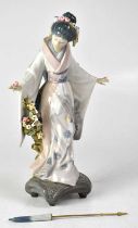 LLADRÓ; a figure of a Geisha standing on a scrolling base, with closed parasol, height 27cm.