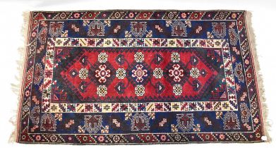 An Eastern hand knotted red and blue ground rug, with three central medallions within a stepped