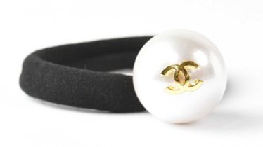 CHANEL; a hair bobble with a large pearlised bead, set with gold-coloured double 'C' logo,