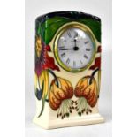 MOORCROFT; an 'Anna Lily' pattern mantel clock, the white enamel dial with Roman numerals, copyright