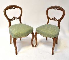 A set of six Victorian walnut balloon back chairs with stuff-over seats and raised on slender