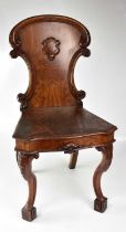 An oak shield back hall chair raised on carved cabriole supports to block feet, height 90cm.