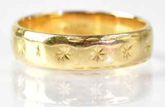 An 18ct yellow gold wedding band with engraved stars, size K, approx. 3.6g.