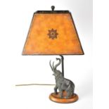 A figural table lamp with bronzed resin elephant figure raised on an oval plinth, height including