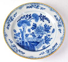 A late 18th century Delftware blue and white charger, painted in the chinoiserie style, with peonies